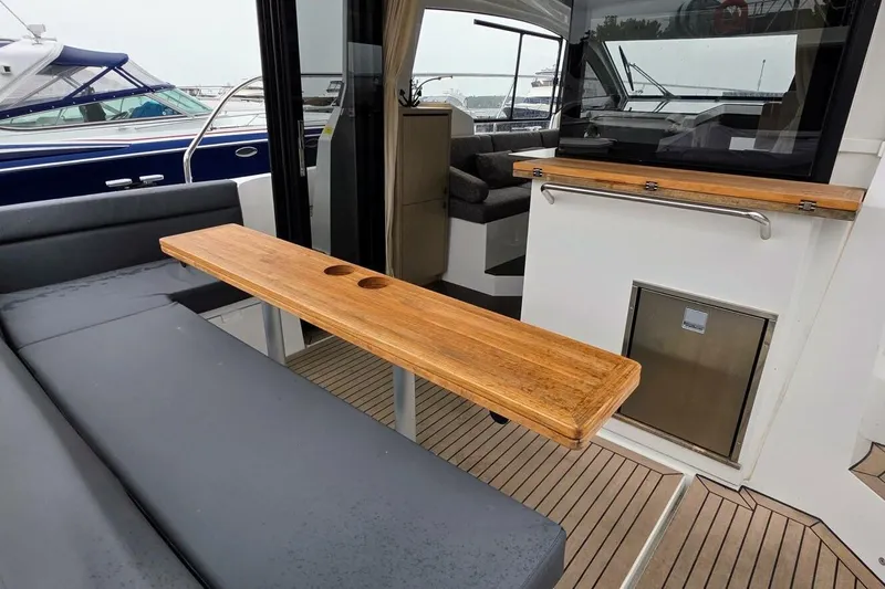  Yacht Photos Pics 2023 Sealine C335V yacht interior with wooden table and seating area.