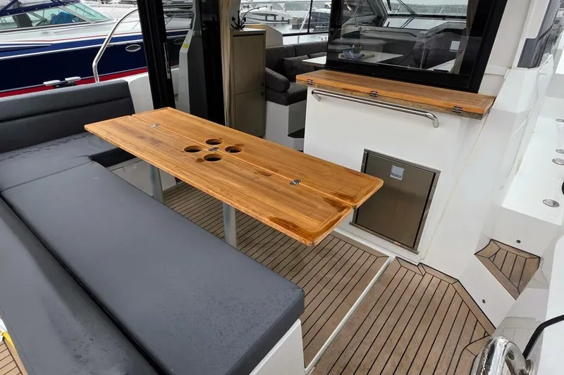  Yacht Photos Pics 2023 Sealine C335V yacht interior with wooden table and cushioned seating.