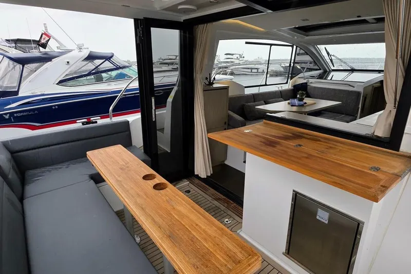  Yacht Photos Pics 2023 Sealine C335V yacht interior with wooden tables and gray seating.