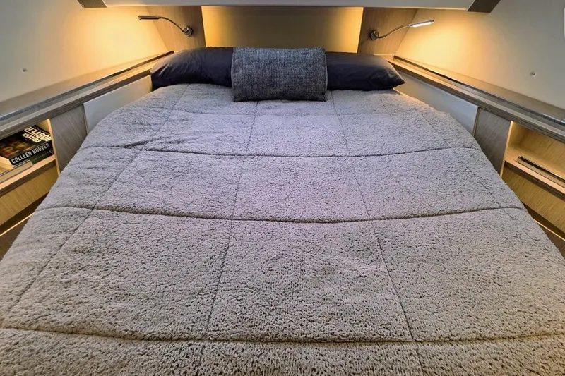  Yacht Photos Pics Luxurious bedroom interior of 2023 Sealine C335V yacht with cozy bedding and ambient lighting.