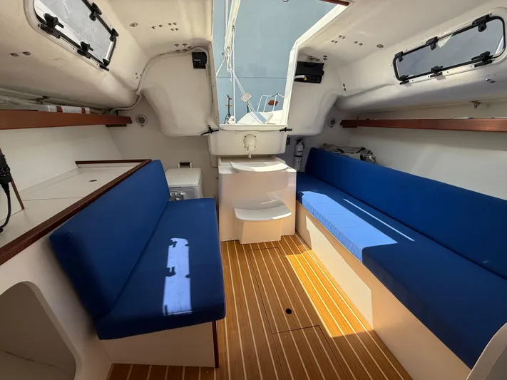 Evelyn Yacht Photos Pics Interior of 2022 J Boats J/9 sailboat with blue seating and wooden flooring.