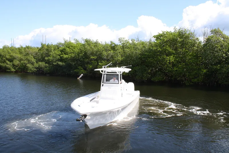  Yacht Photos Pics Limitless 270 boat cruising on a serene waterway, surrounded by lush greenery, 2026 model.