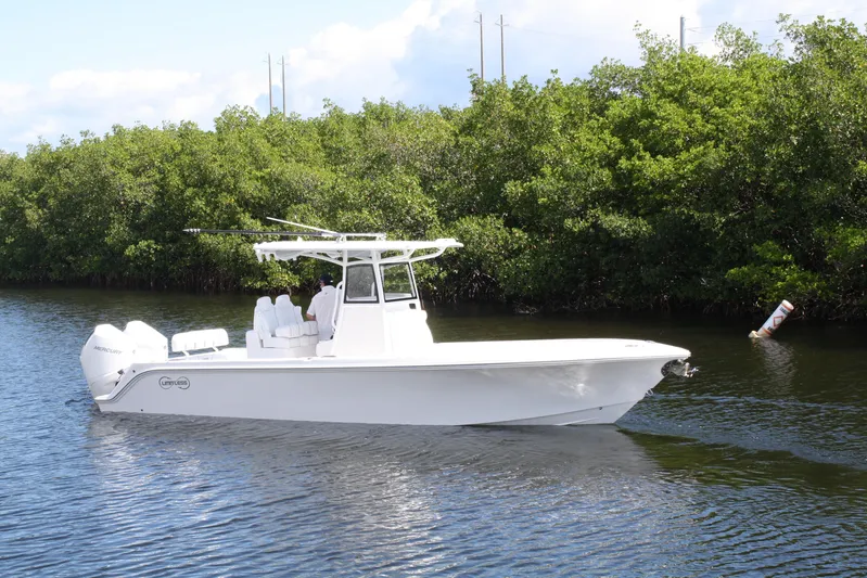  Yacht Photos Pics A sleek 2026 Limitless 270 boat cruising on a calm river near lush greenery.