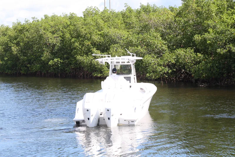  Yacht Photos Pics A 2026 Limitless 270 boat navigating a calm waterway surrounded by lush greenery.