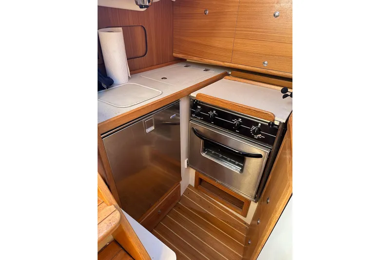  Yacht Photos Pics 2015 Catalina 315 yacht kitchen with stove, oven, and wooden cabinetry.