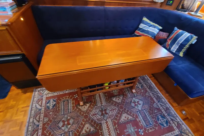 Breakaway Yacht Photos Pics Interior of 2000 Grand Banks 46 Classic with wooden table, blue seating, and patterned rug.