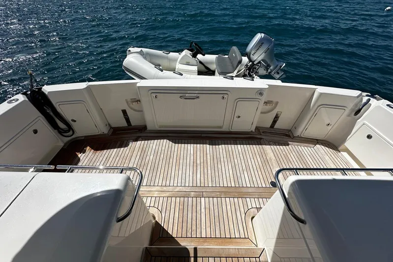  Yacht Photos Pics 2023 Riviera 465 SUV yacht deck with wooden flooring and tender boat on water.