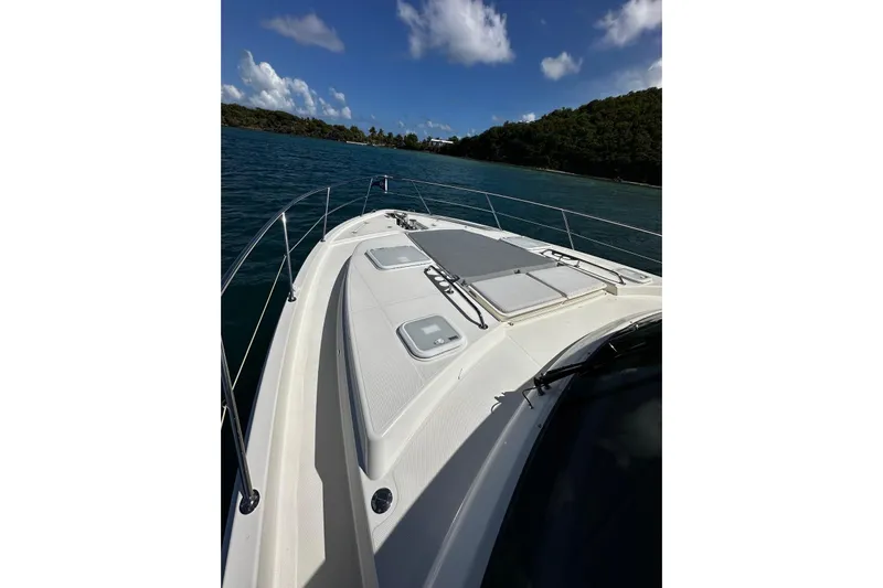  Yacht Photos Pics 2023 Riviera 465 SUV yacht cruising on clear blue waters under a sunny sky.