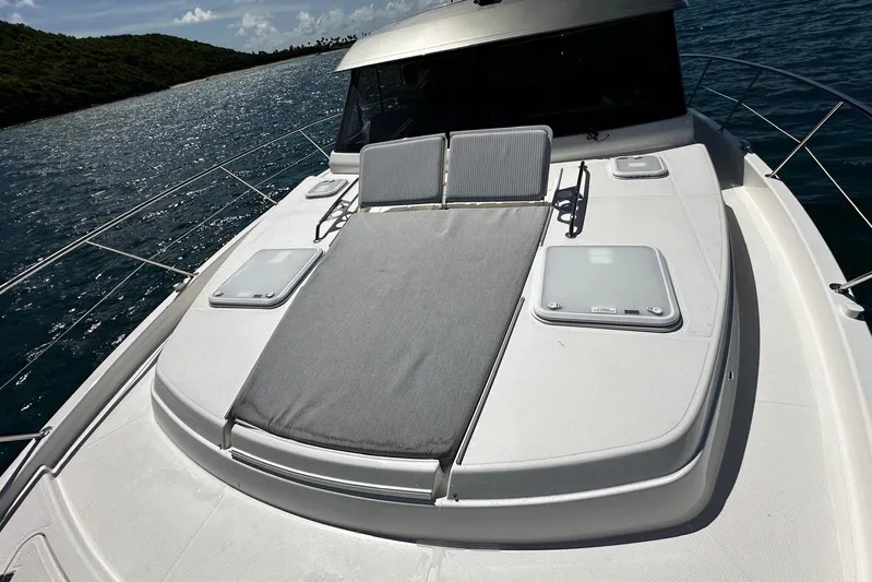  Yacht Photos Pics 2023 Riviera 465 SUV yacht with sunbed on deck, cruising in scenic waters.