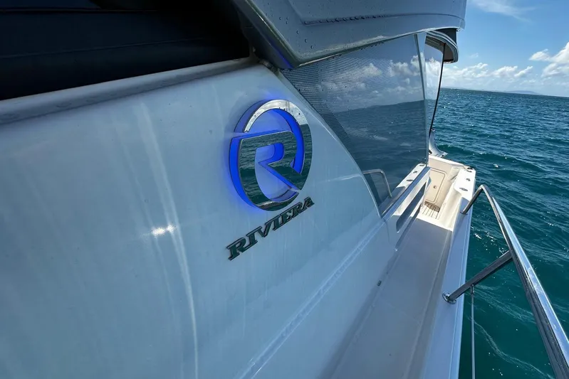  Yacht Photos Pics 2023 Riviera 465 SUV yacht on open water, showcasing sleek design and logo.