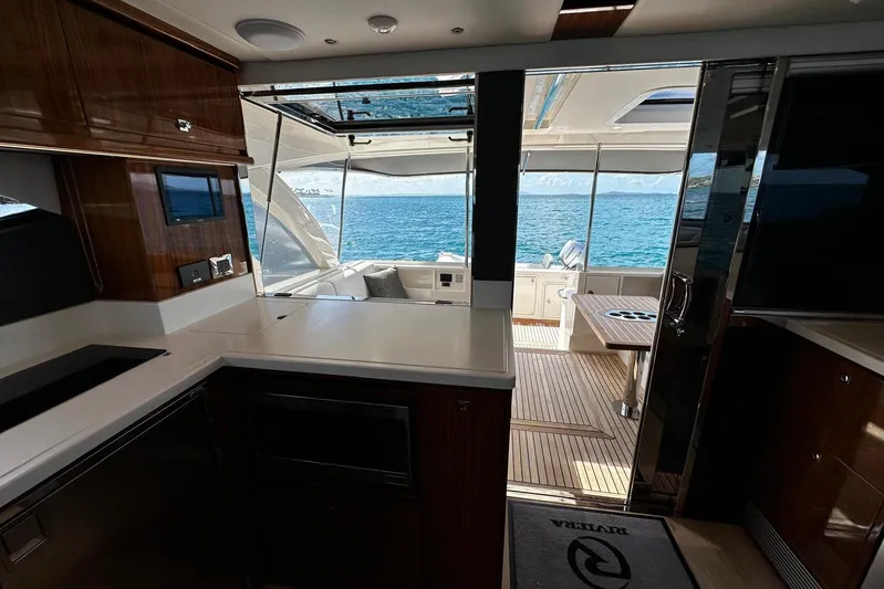 Yacht Photos Pics Interior view of 2023 Riviera 465 SUV yacht, featuring modern kitchen and ocean backdrop.