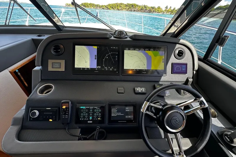  Yacht Photos Pics 2023 Riviera 465 SUV helm with advanced navigation displays and steering wheel, overlooking ocean.