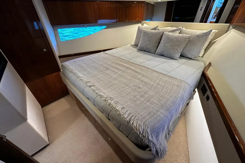 Yacht Photos Pics Luxurious bedroom interior of 2023 Riviera 465 SUV yacht with elegant bedding and wood accents.