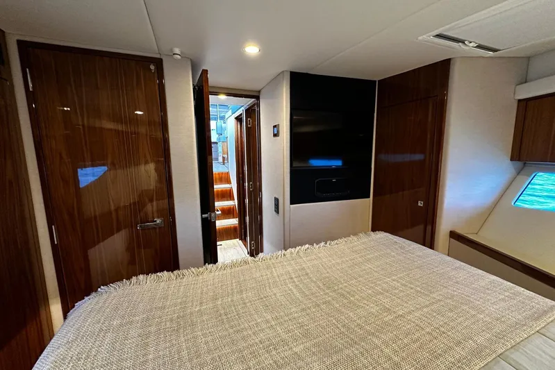  Yacht Photos Pics Luxurious interior of 2023 Riviera 465 SUV yacht bedroom with wooden finishes.