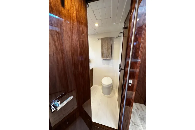  Yacht Photos Pics Luxurious bathroom in 2023 Riviera 465 SUV yacht with wooden finishes and modern fixtures.