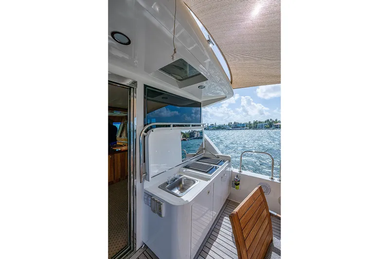 The Usual Yacht Photos Pics Outdoor kitchen on 2000 Horizon 82 yacht with ocean view and wooden chair.