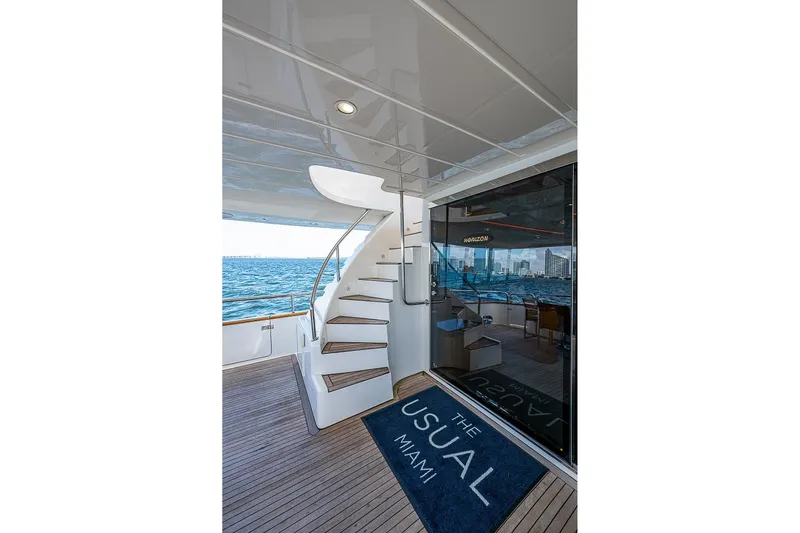 The Usual Yacht Photos Pics Luxury yacht deck with spiral staircase, ocean view, and "The Usual Miami" mat. Horizon 82, 2000.