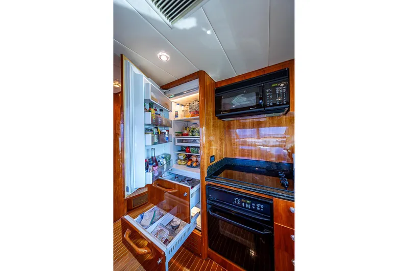 The Usual Yacht Photos Pics Luxurious yacht kitchen with open fridge, microwave, and wooden cabinetry on Horizon 82, 2000 model.