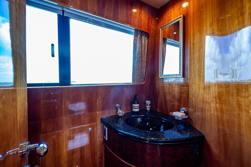 The Usual Yacht Photos Pics Luxurious yacht bathroom with wood paneling, black countertop, and large window, Horizon 82, 2000 model.