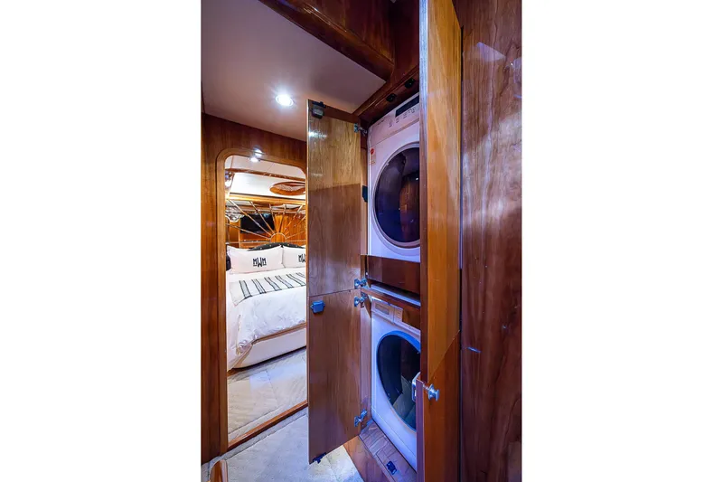 The Usual Yacht Photos Pics Laundry area in Horizon 82 yacht, featuring stacked washer and dryer, adjacent to a cozy bedroom.