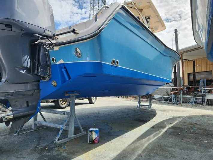 Get Hot Yacht Photos Pics 2011 Grady-White Canyon 306 boat on stands, blue hull, outdoor maintenance area.