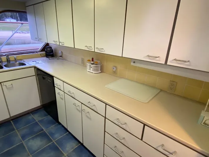  Yacht Photos Pics Spacious kitchen in 1988 Burger 80 Motor Yacht with white cabinets and blue-tiled floor.