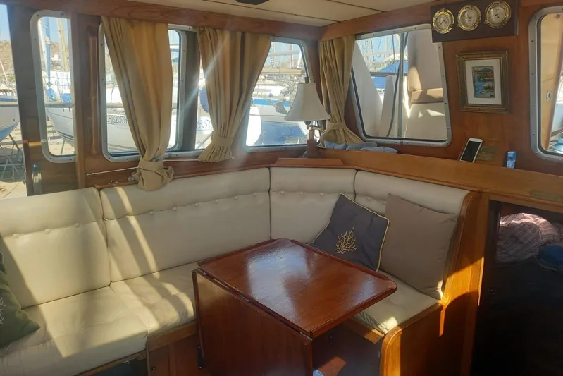  Yacht Photos Pics Cozy interior of 1994 Siltala Nauticat 38 sailboat with cushioned seating and wooden table.