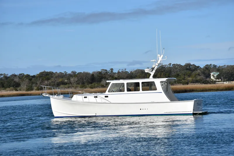 Tomahawk Yacht Photos Pics White 2011 Flowers Hardtop boat on calm water with scenic background.
