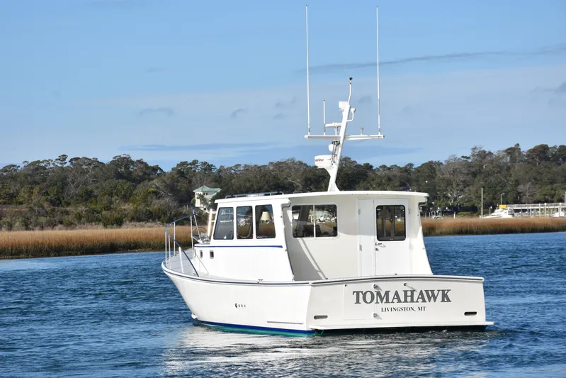 Tomahawk Yacht Photos Pics White Flowers Hardtop boat "Tomahawk" on water, 2011 model, with scenic background.