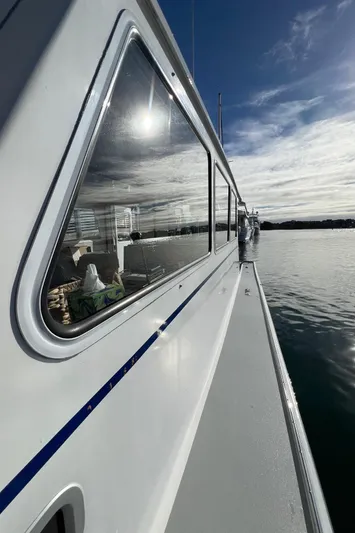 Tomahawk Yacht Photos Pics Side view of 2011 Flowers Hardtop boat on calm water under cloudy sky.
