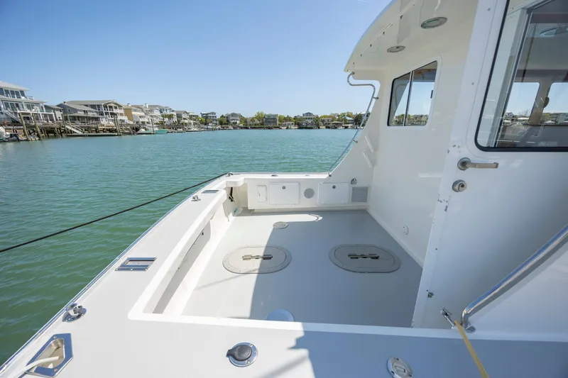 Tomahawk Yacht Photos Pics Spacious deck of 2011 Flowers Hardtop boat on calm water, clear sky background.