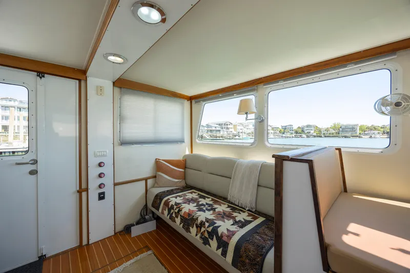 Tomahawk Yacht Photos Pics Cozy boat interior with quilted sofa, large windows, and wood accents, model Flowers Hardtop 2011.