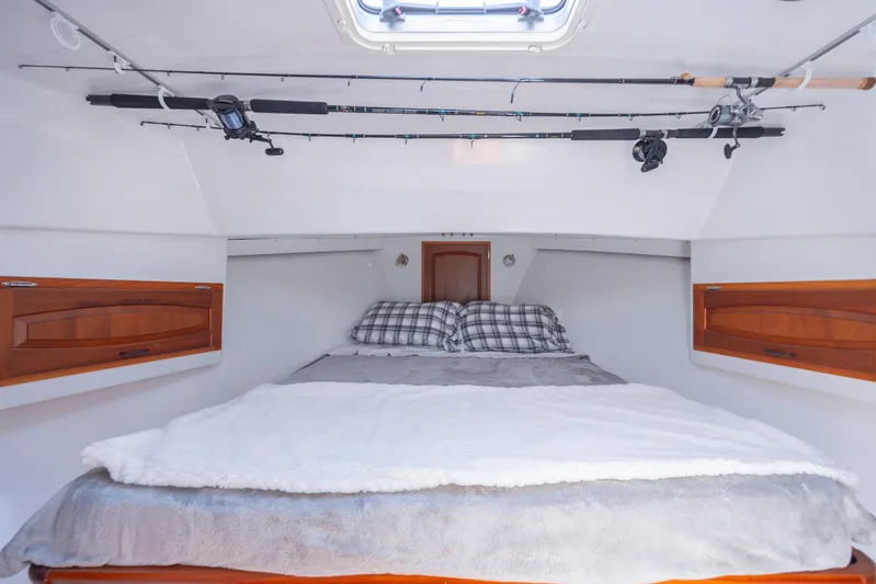 Tomahawk Yacht Photos Pics Cozy boat cabin with bed, fishing rods, and wooden storage, Flowers Hardtop 2011 model.