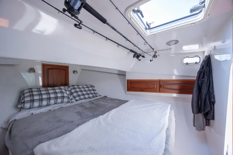 Tomahawk Yacht Photos Pics Cozy cabin interior of 2011 Flowers Hardtop boat with bed, fishing rods, and skylight.