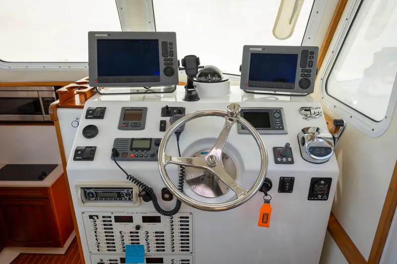 Tomahawk Yacht Photos Pics Boat control panel with steering wheel, navigation screens, and communication devices, Flowers Hardtop 2011 model.