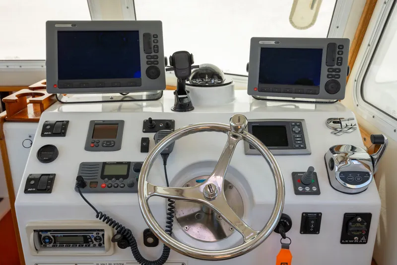 Tomahawk Yacht Photos Pics Boat control panel with steering wheel, navigation screens, and communication devices, Flowers Hardtop 2011 model.