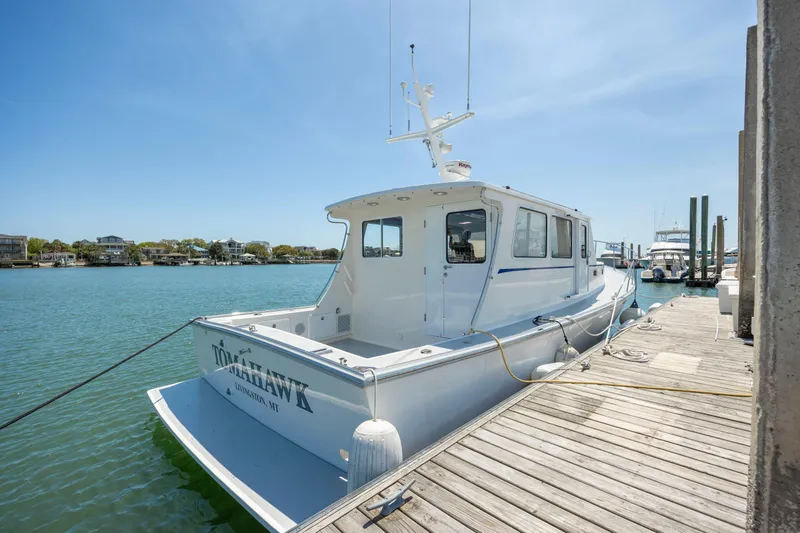 Tomahawk Yacht Photos Pics White Flowers Hardtop boat docked by a wooden pier, clear blue sky, 2011 model.