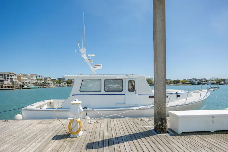 Tomahawk Yacht Photos Pics White Flowers Hardtop boat docked at a marina, clear blue sky, calm water.
