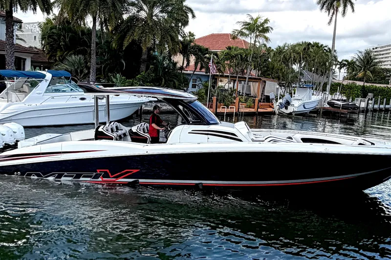 Fire Sale Yacht Photos Pics 2019 MTI V42 boat cruising on a scenic waterway with palm trees in the background.