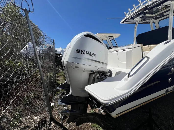  Yacht Photos Pics 2019 Pursuit S 288 Sport boat with Yamaha outboard motor, parked near a fence.
