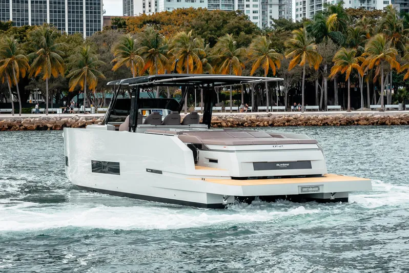  Yacht Photos Pics 2025 De Antonio Yachts D42 Open cruising near a tropical shoreline with palm trees.