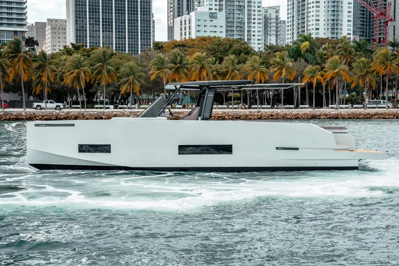  Yacht Photos Pics 2025 De Antonio Yachts D42 Open cruising near a city skyline and palm trees.