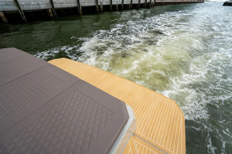  Yacht Photos Pics 2025 De Antonio Yachts D42 Open, rear deck view, cruising on water near a dock.