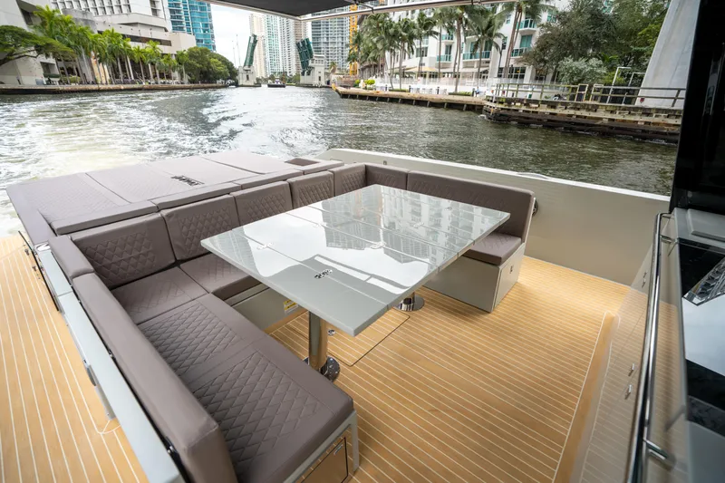  Yacht Photos Pics 2025 De Antonio Yachts D42 Open, elegant deck with seating and table, city waterfront view.