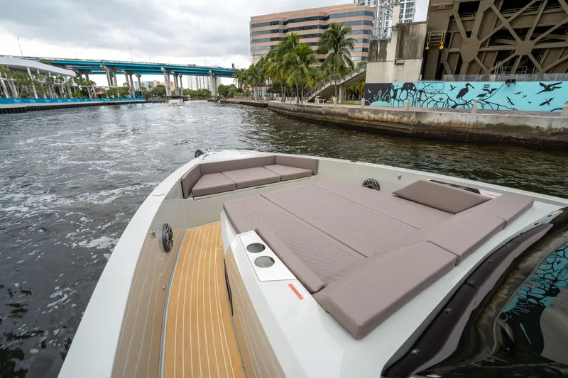  Yacht Photos Pics 2025 De Antonio Yachts D42 Open cruising in urban waterway, featuring spacious deck and modern design.