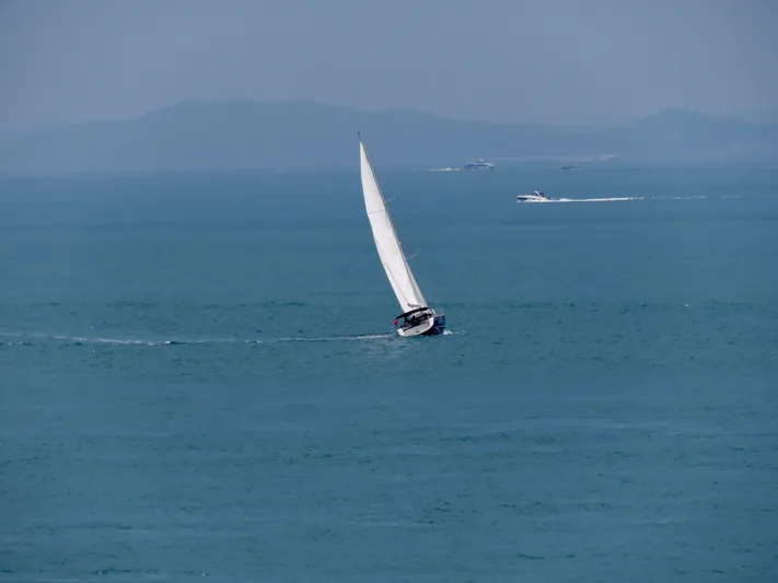  Yacht Photos Pics Sailboat Beneteau Sense 55, 2015 model, cruising on open sea with distant hills.