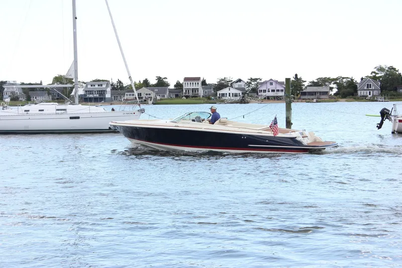 Wahoo Yacht Photos Pics 2013 Chris-Craft Launch 28 boat cruising on a scenic waterfront with houses in the background.