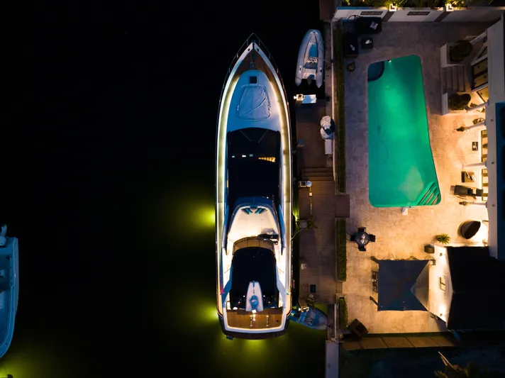  Yacht Photos Pics Aerial view of a 2012 Riva 75 Venere yacht docked beside a pool at night.