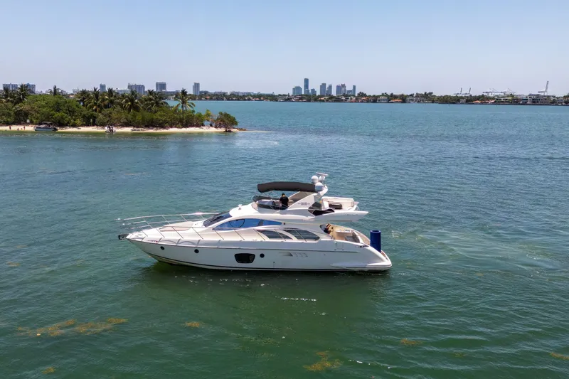  Yacht Photos Pics 2006 Azimut 55E yacht cruising near a tropical island with city skyline in background.