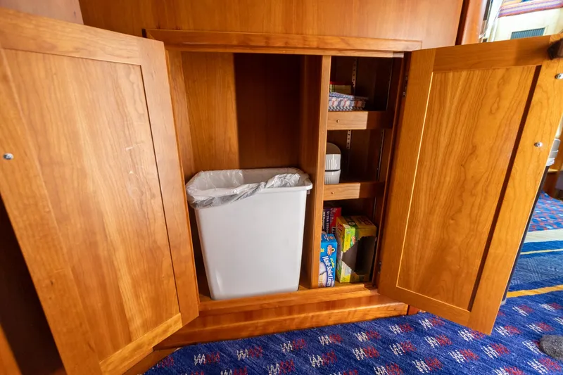  Yacht Photos Pics Wooden cabinet with open doors, revealing a trash bin and shelves, on a Sabre 52 Express yacht.